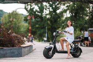 Young beautiful woman and an electric scooter, ecological transport photo