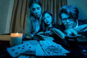 Two women and a guy are reading a mysterious books, close view photo