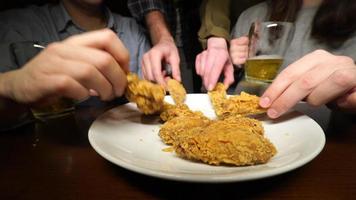 Friends take apart fried legs and wings from a plate in a pub photo