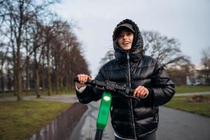 Woman in a jacket on an electric scooter in an autumn park. photo