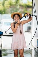 Woman with high pressure hose at car wash photo