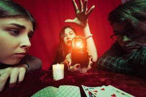 Group of people and woman fortune teller with crystal ball photo