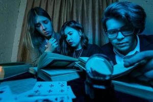 Two women and a guy are reading a mysterious books, close view photo