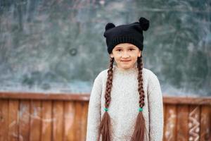 Little girl in a hat posing on the background of the school blackboard photo
