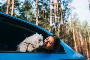 mujer joven y perro miran por la ventana del auto foto