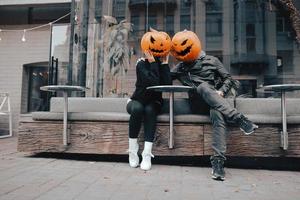 Guy and girl with pumpkin heads in a street cafe photo