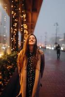 mujer por escaparate iluminado en la calle de la ciudad. foto