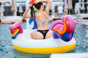 Woman on inflatable unicorn toy mattress float in pool. photo