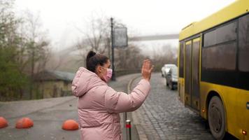 mujer joven de pie en la carretera al aire libre levantando la mano a un lado tomando un taxi foto