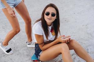 chica con un teléfono inteligente sentada en una patineta foto