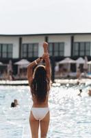 mujer joven en el fondo de la piscina en traje de baño blanco. foto