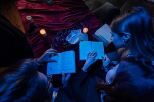 Two women and a guy are reading a mysterious books, close view photo