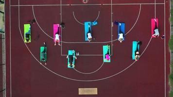 Group of young people doing workout on the red sportground. Top aerial view. photo