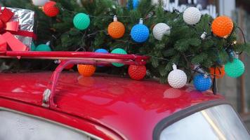 coche retro rojo con un abeto de árbol de navidad atado al techo. foto