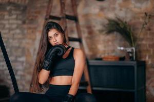 Beautiful young fitness girl posing at camera in black boxing glove photo