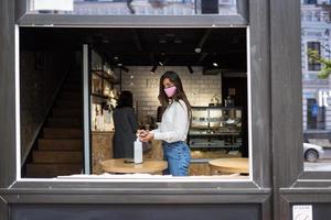 Woman using sanitizer gel cleans hands of coronavirus virus at cafe. photo