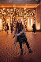 Girl on the background of the illuminated entrance to the building photo