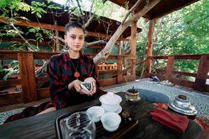 mujer joven sosteniendo un pequeño tazón de té de hierbas verdes foto