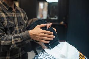 Barber preparing man face for shaving with hot towel in barber shop photo