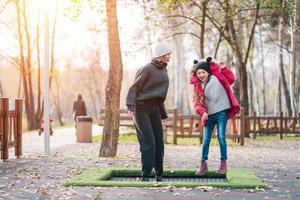 Mom and her daughter jumping together on trampoline in autumn park photo