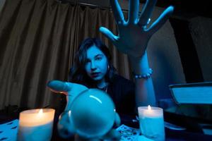 Woman fortune-teller guesses fate of night at table with candles photo