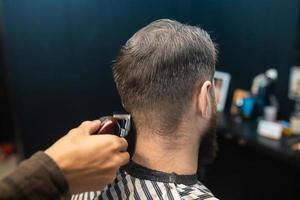 Master in barbershop makes men's haircutting with hair clipper photo