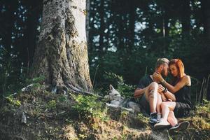 beautiful couple sitting in a forest near the tree photo