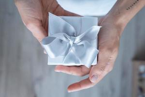 Woman hands holding Gift box with white bow, close-up photo