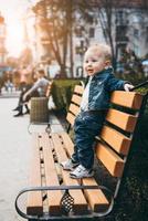 niño de pie en el banco de madera en el parque foto