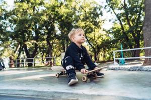 Young kid sitting in the park on a skateboard. photo