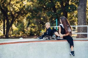 bella joven hipster mamá e hijo pequeño en el skatepark foto