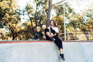 bella joven hipster mamá e hijo pequeño en el skatepark foto