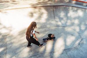 joven madre le enseña a su hijo pequeño a andar en patineta foto