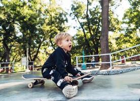 Young kid sitting in the park on a skateboard. photo