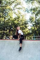 Beautiful young hipster girl sitting on the edge of a ramp photo