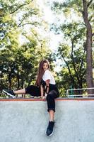 Beautiful young hipster girl sitting on the edge of a ramp photo