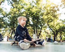 Young kid sitting in the park on a skateboard. photo