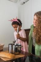 Happy mommy and daughter girl having fun while cooking in kitchen. photo