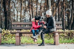 Happy mother and her daughter with dog resting on a bench photo