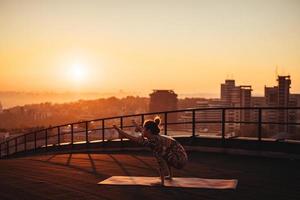 mujer haciendo yoga en la azotea de un rascacielos en la gran ciudad. foto