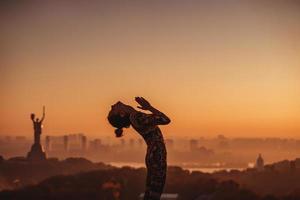 Woman doing yoga on the roof of a skyscraper in big city. photo