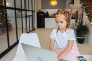 niña usando una computadora de tableta sentada en la mesa foto