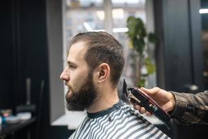 Master in barbershop makes men's haircutting with hair clipper photo