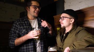 jóvenes amigos divirtiéndose juntos bebiendo cerveza y tintineando vasos en un pub. foto