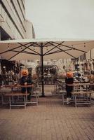 Guy and girl with pumpkin heads in a street cafe photo