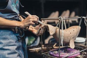 Close-up view of female hands gently handling a clay whale in workshop. photo