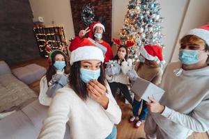 Multiethnic group of friends in Santa hats with gifts in hands. photo