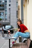 mujer bloguera en un café de verano transmitiendo en la calle. foto