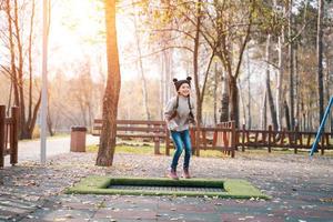 colegiala feliz saltando sobre un pequeño trampolín en el parque foto