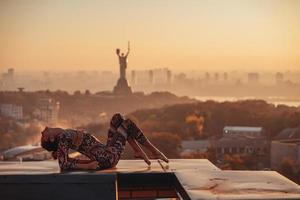 mujer haciendo yoga en la azotea de un rascacielos en la gran ciudad. foto